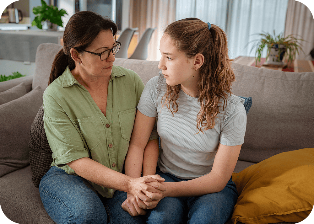 Woman and a girl sitting on a couch, holding hands